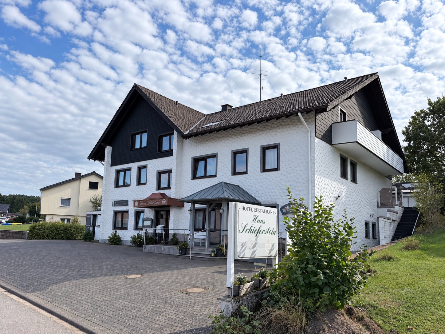 Haus Schieferstein von der Stra&szlig;e aus, mit Hotelschild und Parkplatz